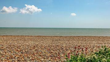 A pebbled beach with a clear sky and calm sea.