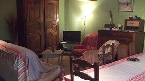 A living room with a sofa, a television, a table, and a chair. - Le gîte du "Grand Reu" - Gîte Anna (Corancy)