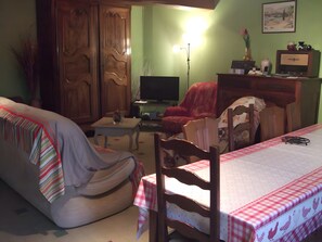 A living room with a sofa, a television, a table, and a chair. - Le gîte du "Grand Reu" - Gîte Anna (Corancy)