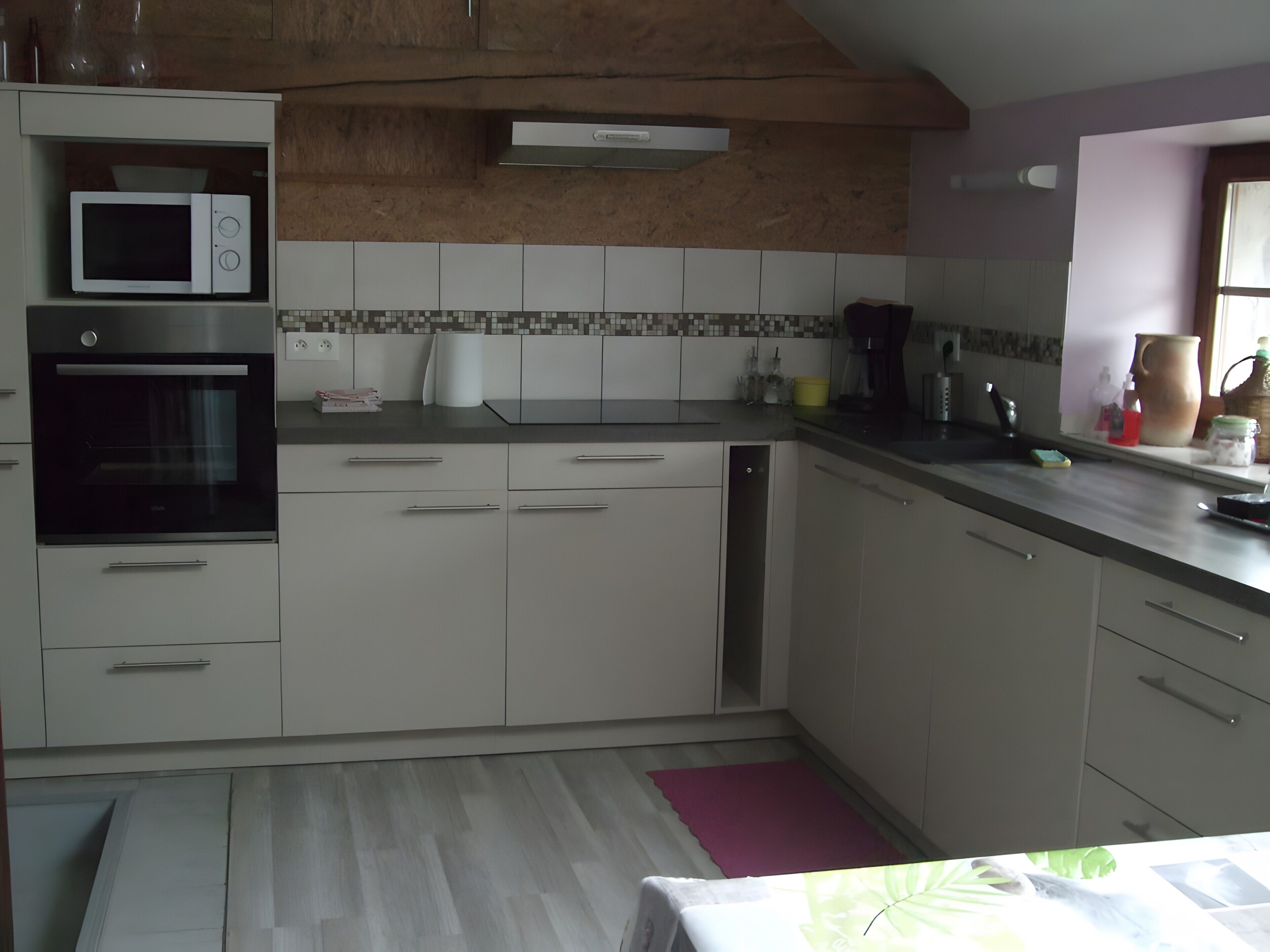 A kitchen with white cabinets, a microwave, an oven, and a tiled backsplash.