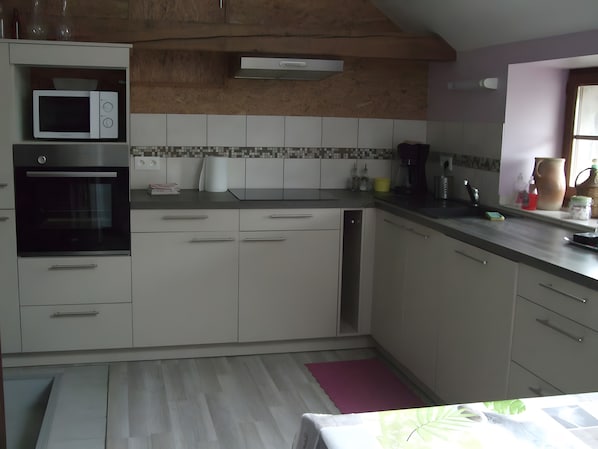 A kitchen with white cabinets, a microwave, an oven, and a tiled backsplash.