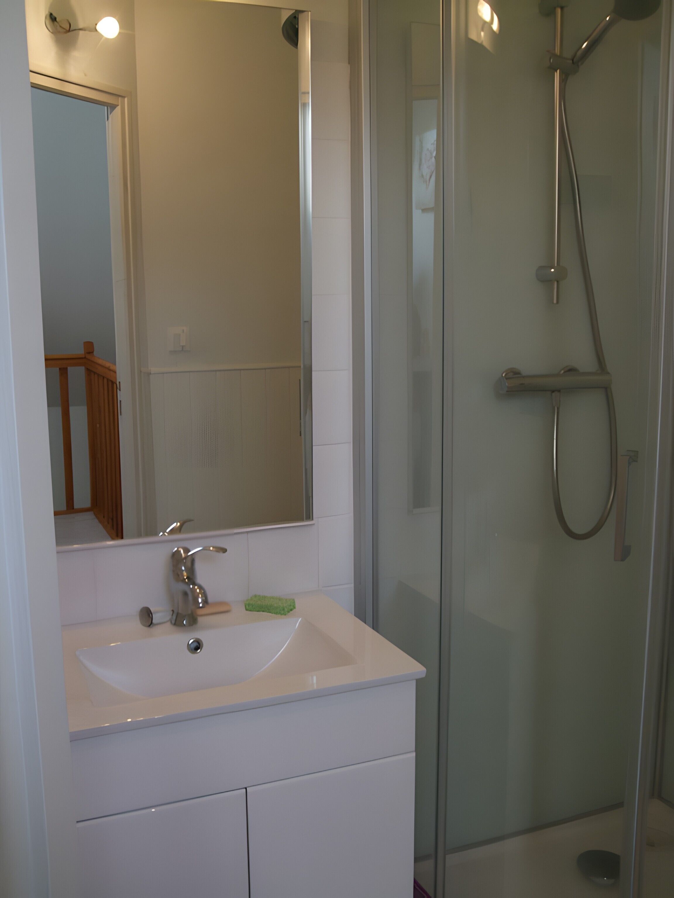 Ein Badezimmer mit Waschbecken, Spiegel und einer Duschkabine aus Glas.