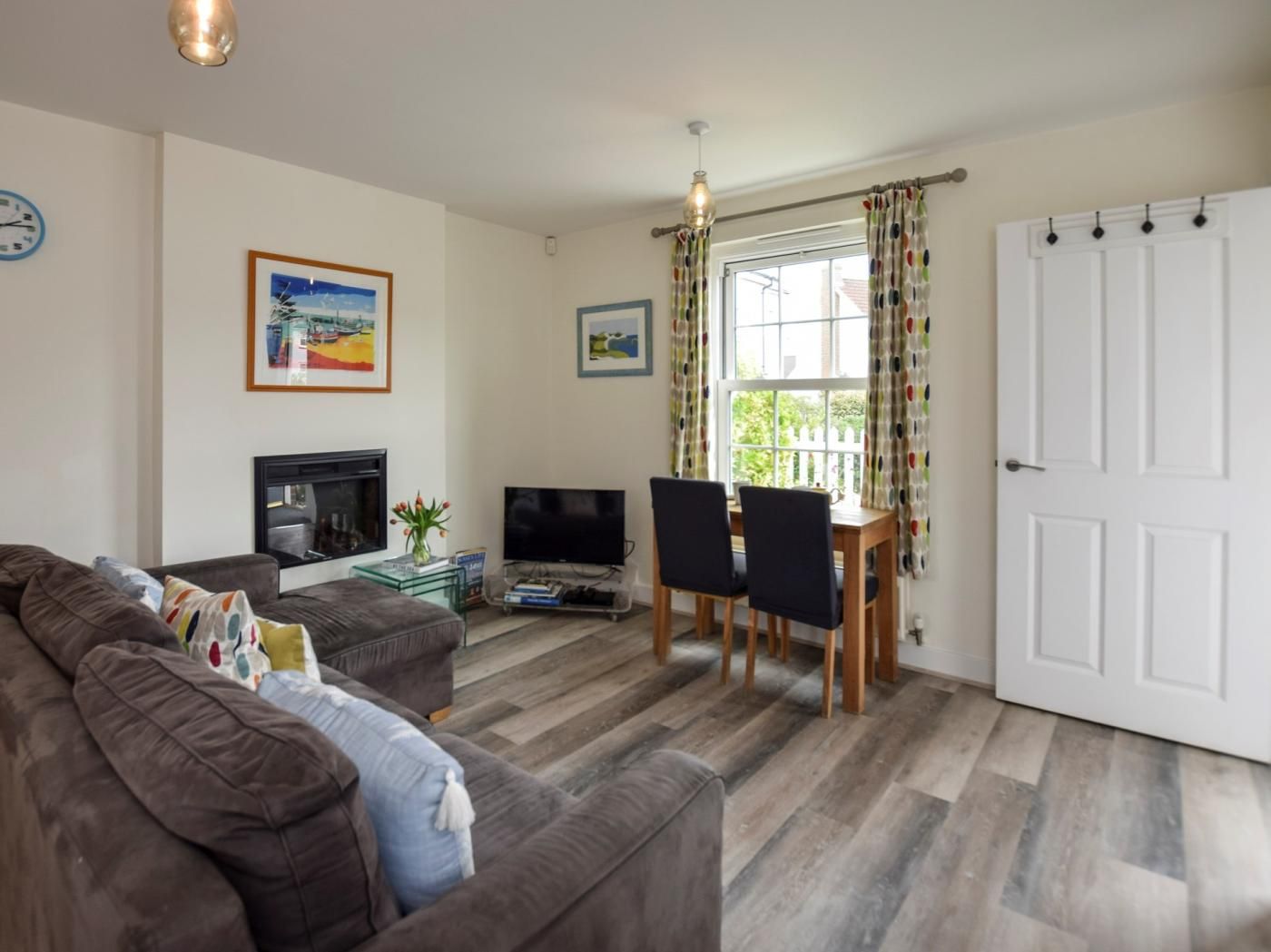 A living room with a sofa, TV, fireplace, dining table with chairs, and a door.