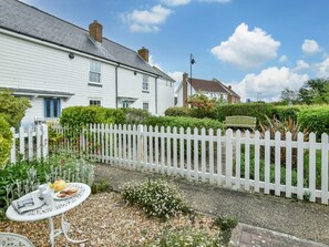 A white picket fence, a white house, and a garden with a table and chairs. - 2 Bed in Camber (oc-bt084) (Camber)