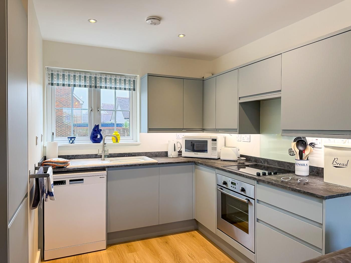 A modern kitchen with a dishwasher, microwave, toaster, and oven.