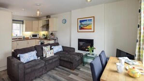 A compact living space with a kitchenette, a sofa set, a dining table, and a flat-screen TV. - 2 Bed in Camber (oc-bt084) (Camber)