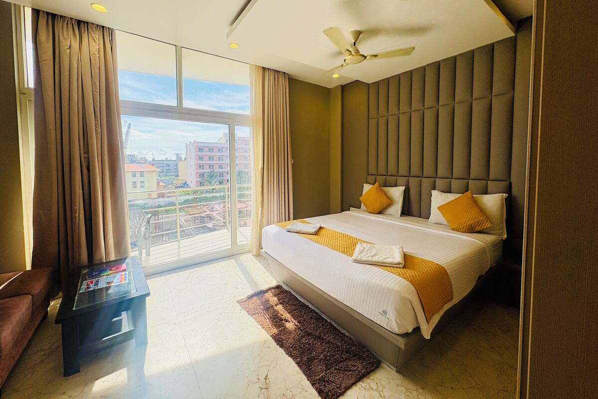 Una habitación de hotel moderna con una cama grande, un ventilador de techo y vistas a la ciudad.