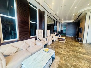 Un hall d’hôtel moderne avec un canapé, des fauteuils, une table basse et une grande fenêtre.