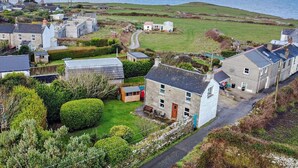 A coastal village with stone houses, a grassy field, and a view of the sea. - 1 Bed in Penzance (oc-47390) (Pendeen)
