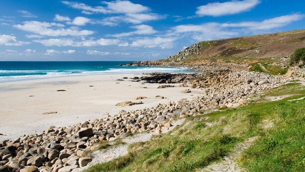 A beach with a rocky shoreline, a clear sky, and a distant view of the ocean. - 1 Bed in Penzance (oc-47390) (Pendeen)