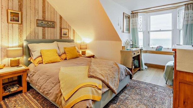 Een slaapkamer met een bed, nachtkastjes, een bureau en een raam met uitzicht.