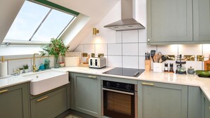 Een moderne keuken met dakraam, een inbouwoven en diverse keukenapparaten en keukengerei.