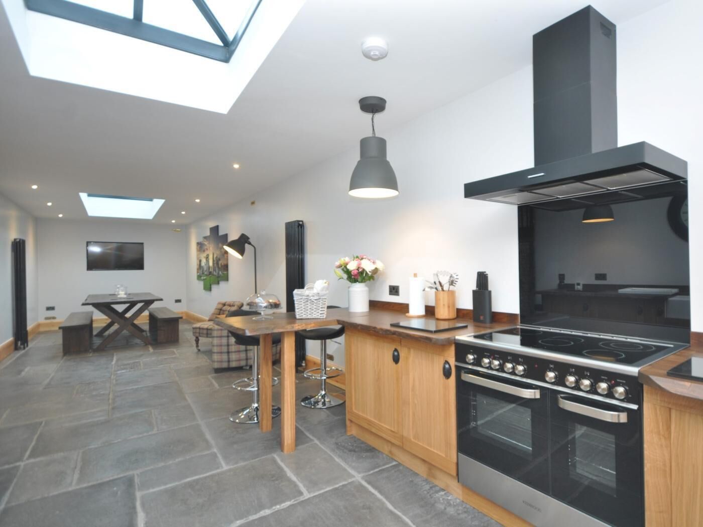 A modern kitchen with a large stove, wooden cabinets, and a skylight.
