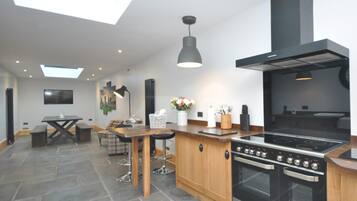 A modern kitchen with a large stove, wooden cabinets, and a skylight.