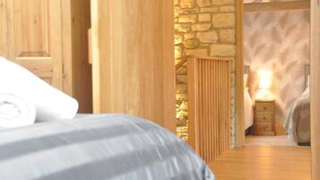 A bedroom with a bed, wooden walls, a stone wall, and a nightstand with a lamp.