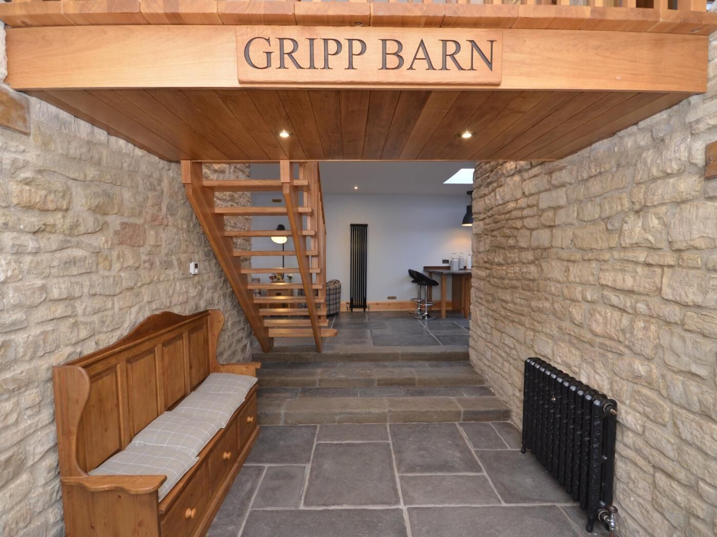 A staircase leading to a loft area with a wooden bench and a sign reading 'GRIPP BARN'.