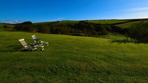 A grassy field with white lounge chairs and a clear blue sky. - 4 Bed in Boscastle (oc-47035) (Forrabury and Minster)
