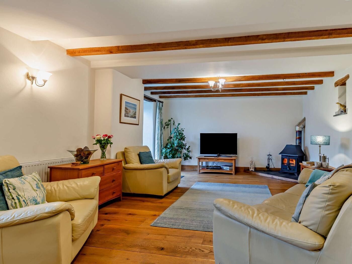 A living room with two sofas, a TV, a fireplace, and wooden beams on the ceiling.