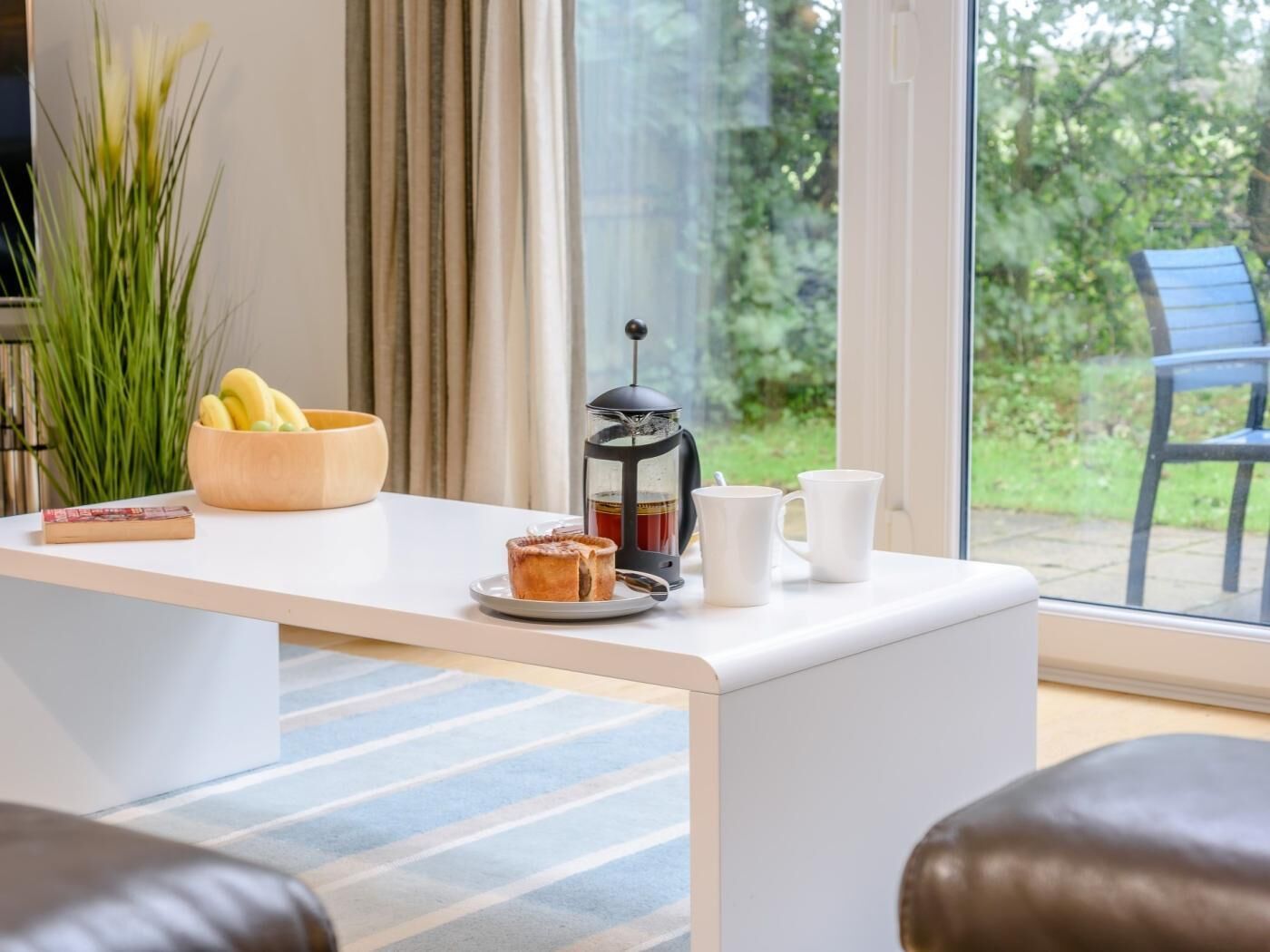 Een moderne keuken met een koffiezetapparaat, een schaal bananen en een boek op het aanrecht.