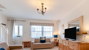Ein Wohnzimmer mit Sofa, Fernseher, Holzschrank und einer Kandelaber.