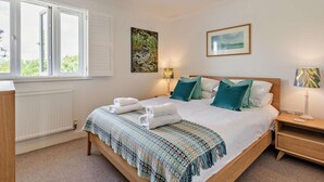 A bedroom with a bed, bedside tables, a radiator, a window, and artwork on the walls. - 4 Bed in Rye- (oc-bt104) (Rye)