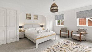 Una camera da letto con un letto, due poltrone, una lampada a sospensione e una finestra con vista.