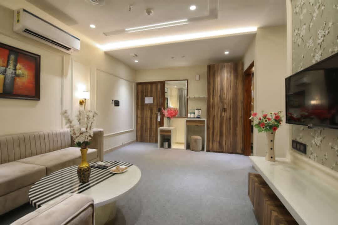 A modern living room with a sofa, a coffee table, a TV, and a kitchen area in the background.