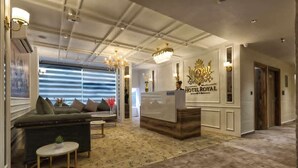 Un hall d’hôtel comprenant un comptoir d’accueil, un canapé, une petite table et un lustre.
