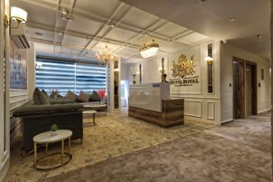 A hotel lobby with a reception desk, a sofa, a small table, and a chandelier.