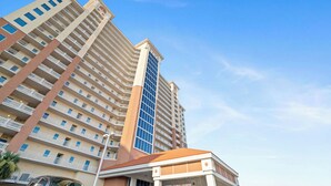 Un hotel de varios pisos con una torre central destacada, múltiples balcones y cielo despejado.