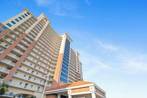 A multi-story hotel with a prominent central tower, multiple balconies, and a clear sky. - San Carlos 1808 by Liquid Life (Gulf Shores)