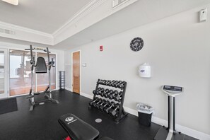 A gym with exercise equipment, a dumbbell rack, a bench, a scale, and a wall clock. - San Carlos 1808 by Liquid Life (Gulf Shores)