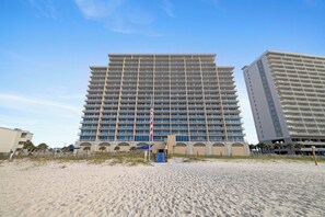 A multi-story hotel with a uniform facade, located on a sandy beach with a clear sky. - San Carlos 1808 by Liquid Life (Gulf Shores)