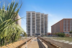 Un hôtel à plusieurs étages doté de balcons, d’une promenade en bois et offrant une vue sur un ciel dégagé.
