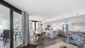 Et moderne køkken med en central ø, et spiseområde med stole og en opholdsstue med en sofa.