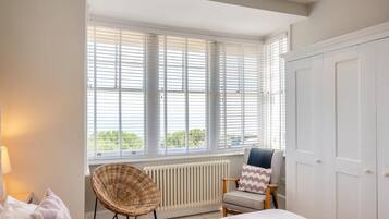 A bedroom with a bed, a chair, a radiator, and a window with blinds.