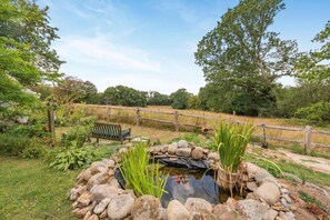 Ein Garten mit Teich, Holzzaun und Bank.