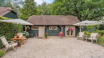 A rustic cottage with a gravel patio, outdoor seating, and a garden.