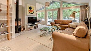 Ein modernes Wohnzimmer mit Kamin, einer Couch, einem Couchtisch und einem Fernseher.