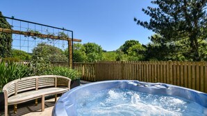 Ein Whirlpool in einem Garten mit einer Holzbank und einem Holzzaun.