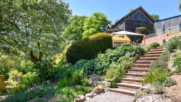 Ein Garten mit einem Kiesweg, der zu einem Holzhaus mit gelber Tür führt.