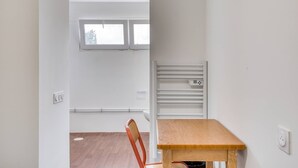 A room with a wooden table, a chair, a radiator, and a window. - Room with Shared Terrace and Wi-Fi, 10 Minutes from the Beach (Mudaison)