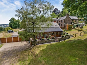 A stone building with a covered porch, surrounded by a fenced garden area with potted plants. - 1 Bed in Abergavenny (oc-47886) (Pantygelli)