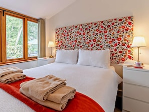A hotel room with a bed, two bedside tables, a window, and a floral-patterned headboard. - 1 Bed in Abergavenny (oc-47886) (Pantygelli)