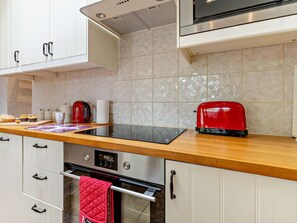 Una cocina moderna con armarios blancos, un tostador rojo, una cafetera y un panel de control digital para el horno.