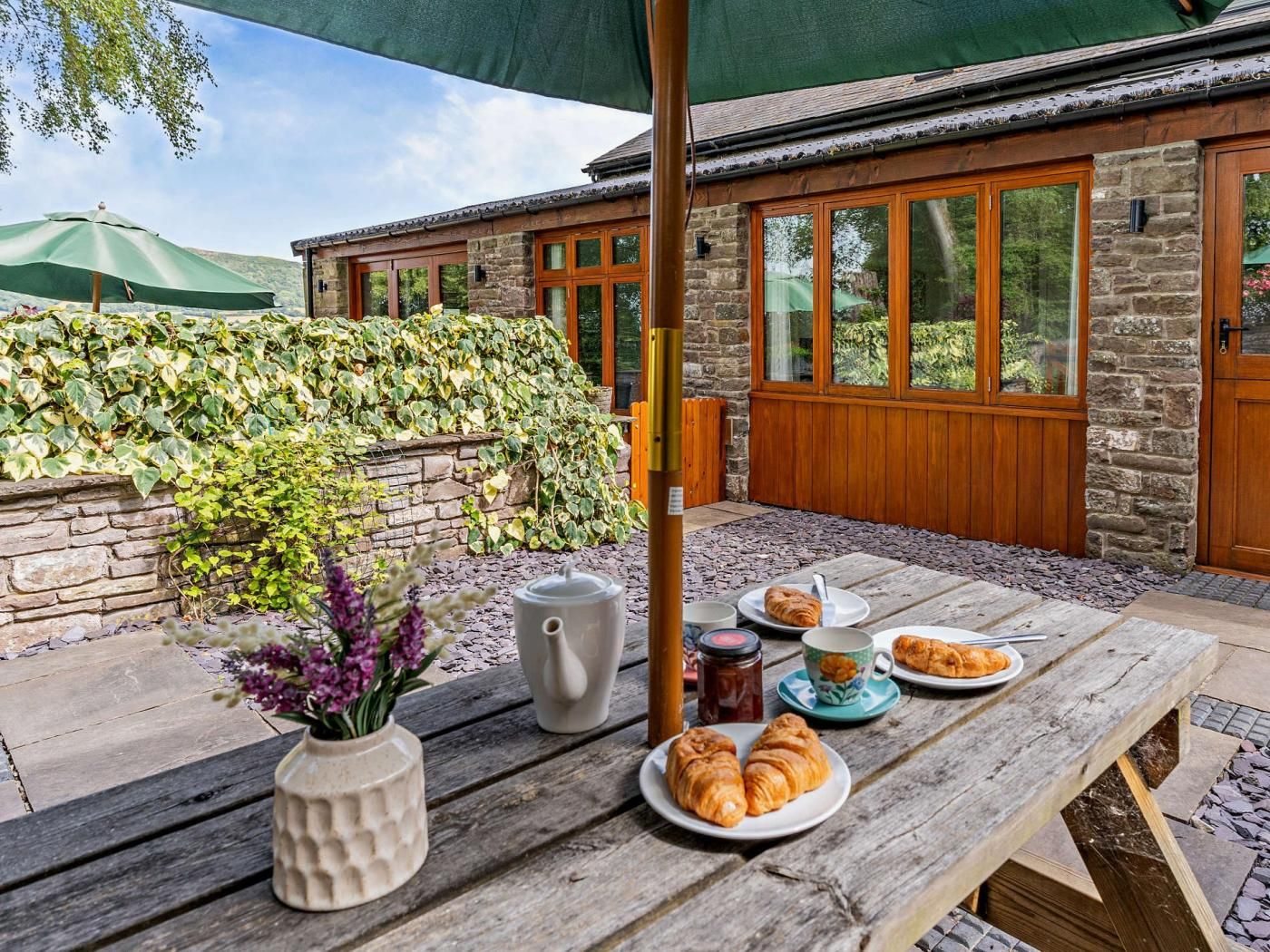 Un espace de restauration extérieur rustique, avec des murs en pierre, des portes en bois et une vue sur un paysage naturel.