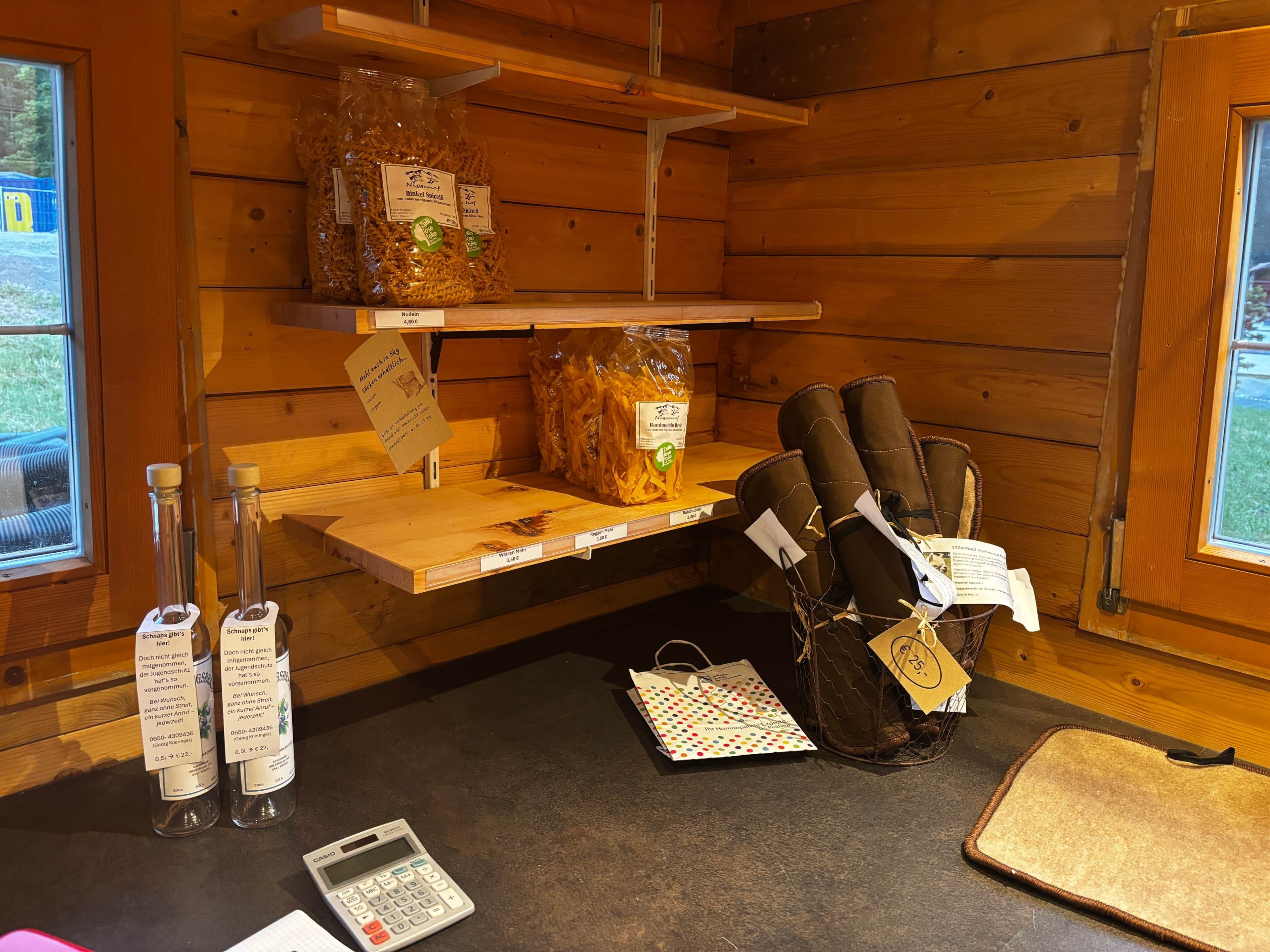 A wooden cabin interior with shelves displaying snacks, a calculator, and a woven bag.