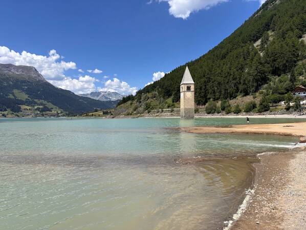A tower by a lake with mountains in the background.
