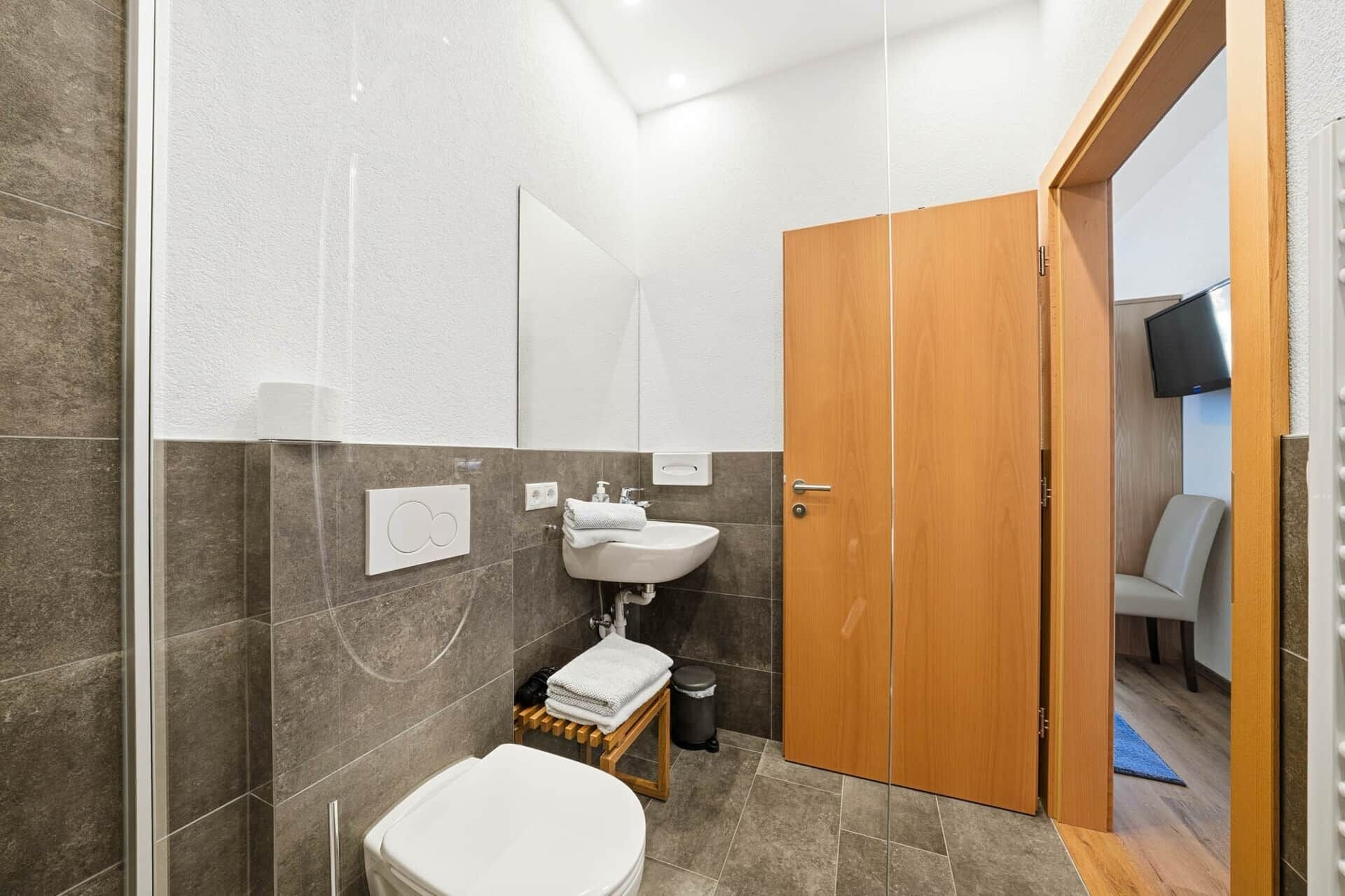 A modern bathroom with a toilet, sink, and shower.