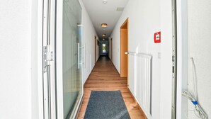 En hall med en glasdörr till vänster, ett trägolv och ett element till höger.